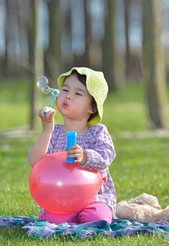 little girl is blowing a soap bubbles in forest