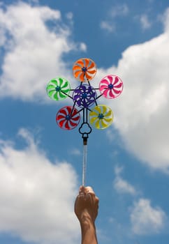 hand hold pinwheel on blue sky background