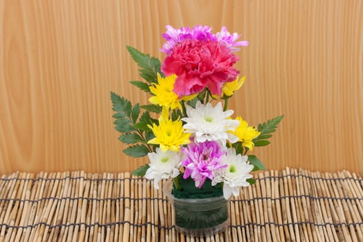 Colorful flower bouquet arrangement in vase on wood background