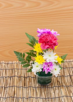 Colorful flower bouquet arrangement in vase on wood background