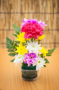 Colorful flower bouquet arrangement in vase on wood background