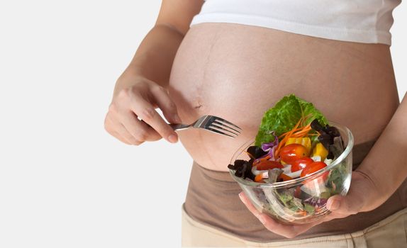 Pregnant woman's belly and vegetable salad. Healthy nutrition.