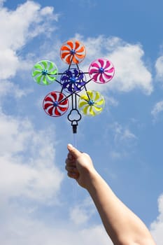 hand hold pinwheel on blue sky background