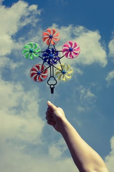 vintage effect style of hand hold pinwheel on blue sky background