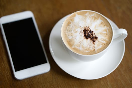 Cup of mocha coffee and smart phone on the table