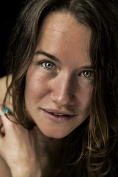 Close up portrait of woman looking straight, isolated on black background.