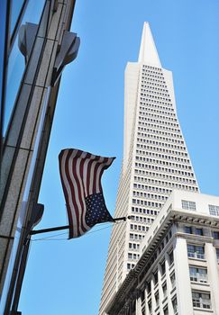 American flag hanging on building in scyscraper background