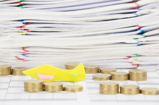 Close up airplane among step pile of gold coins on finance account have overload of paperwork with colorful paperclip as background.