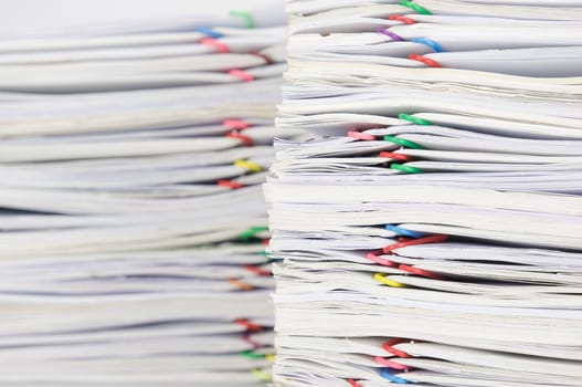 Overload paper of receipt and report with colorful paperclip on table.