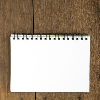 The close up of blank white notebook on wooden plank background.