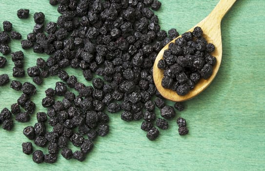 Dried chokeberry fruits (Aronia melanocarpa) in wooden spoon