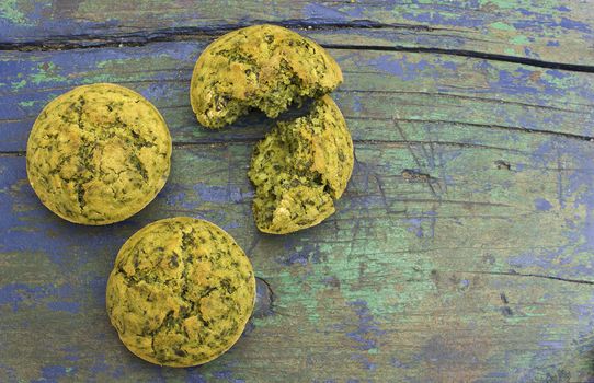 Freshly baked snack muffins with spinach on wooden surface