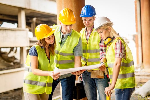 Four construction architects review plan in front building damaged in the disaster.