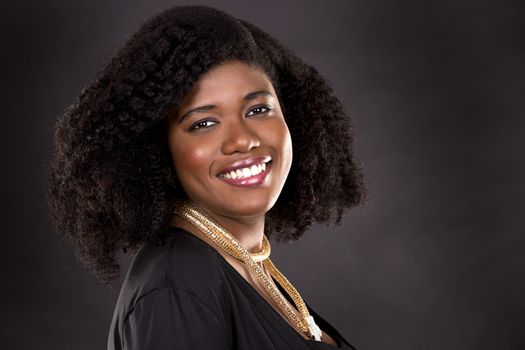 beautiful young black woman is wearing dark dress on grey background