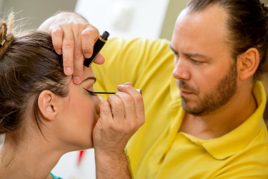 Close up of a make-up man artist getting eyeliner to model.