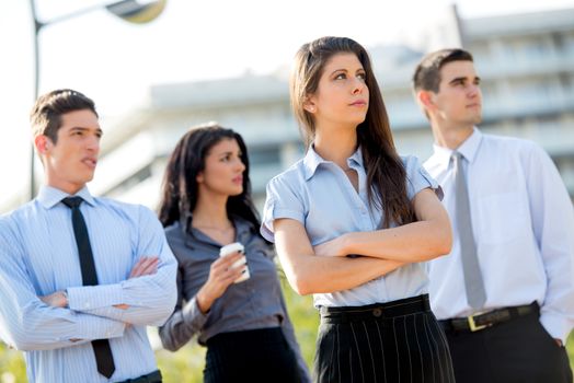 Young successful businesswoman elegantly dressed with his team on a break standing outside enjoying the beautiful day.