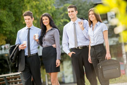 Successful young business team during a coffee break, walking on a park and enjoying a sunny day.