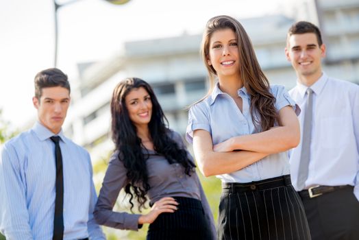 Group of young business people elegantly dressed standing outside enjoying the beautiful day. Looking at camera.