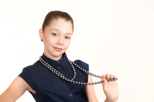 Portrait of the girl of the teenager in a suit with a beads on a white background