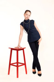 The girl the teenager in a suit with a beads about a red chair on a white background