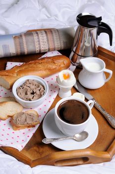 Breakfast on a tray with a cup of coffee, toast with liver pate, Soft-boiled egg and a newspaper