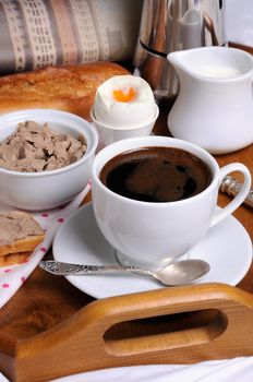 Breakfast on a tray with a cup of coffee, toast with liver pate, Soft-boiled egg and a newspaper