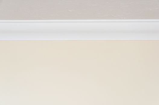 Close up of white ceiling moulding and light brown wall for background with copy space at top and bottom