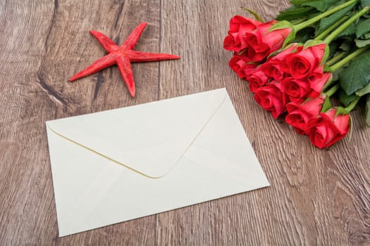 Envelope, red starfish and roses on a wooden background