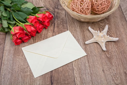 Envelope, white starfish and roses on a wooden background