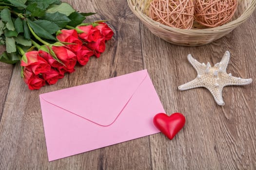 Envelope, roses and white starfish on a wooden background