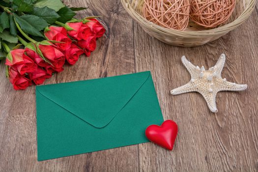 Envelope, roses and white starfish on a wooden background