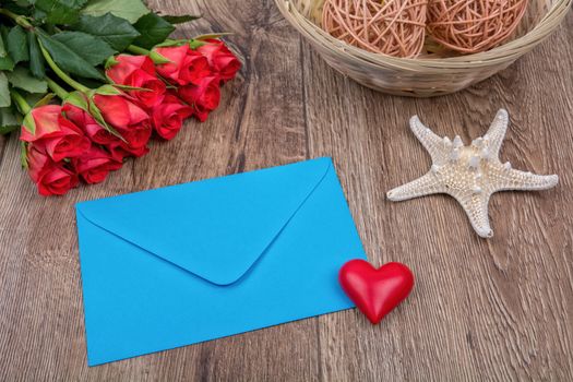 Envelope, roses and white starfish on a wooden background