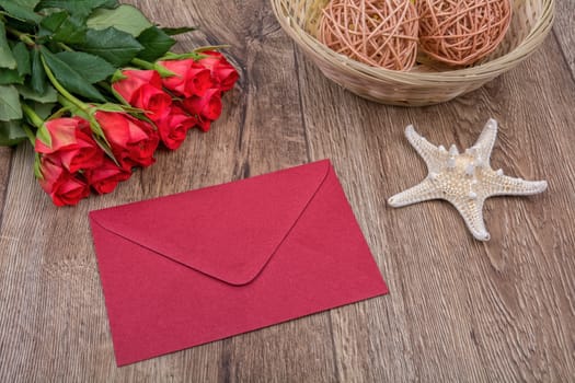 Envelope, white starfish and roses on a wooden background