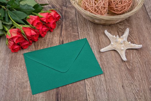 Envelope, white starfish and roses on a wooden background