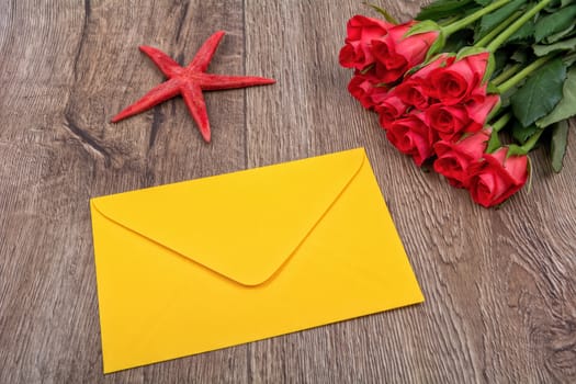 Envelope, red starfish and roses on a wooden background