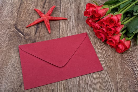 Envelope, red starfish and roses on a wooden background