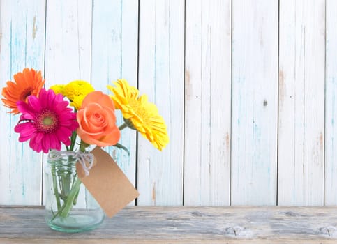 Mixed variety of flowers in a glass jar over a white background