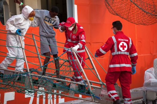 ITALY, Palermo: Medical workers assist a migrant off the Siem Pilot on April 13, 2016 in Palermo, Italy.The vessel has been a major transporter of migrants fleeing the Middle East and Africa to Europe. 