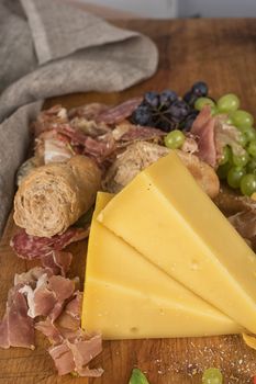 Fresh grapes, cheese bacon berries and salami on wooden table