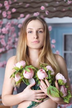 Girl with pink peonies bouquet at wall