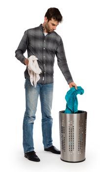 Young man putting a dirty towel in a laundry basket, isolated