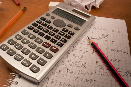 Messy table with notebook, pencils, crumpled papers and calculator