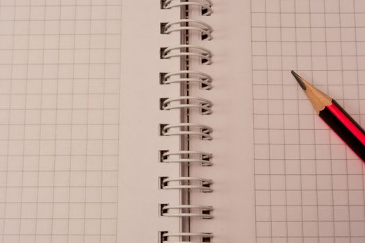 White empty notebook with pencil on top of it.