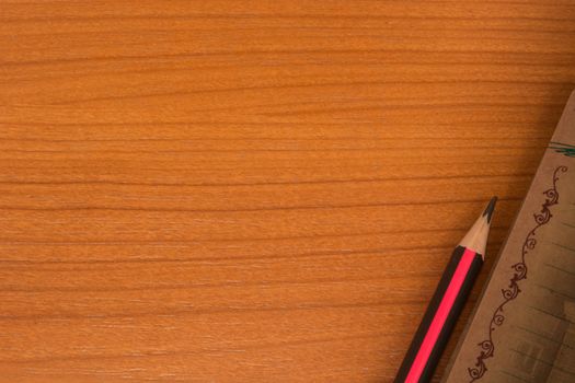 Wooden table with notebook and pencil in one corner