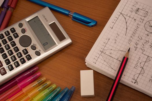 Colorful pencils, calculator, eraser  and notebook on the table