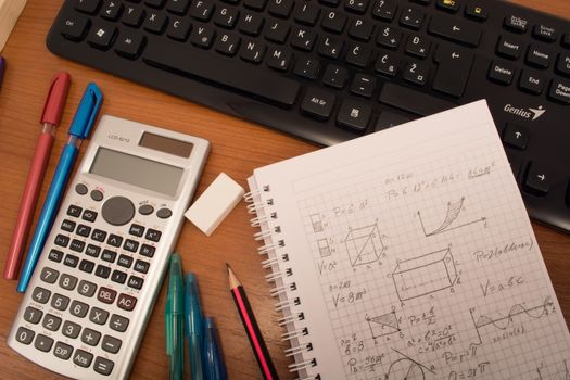 Computer keyboard, calculator, colorful pencils, eraser  and notebook on the table