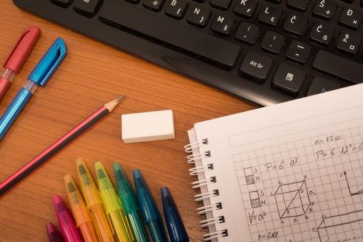 Computer keyboard, colorful pencils, eraser  and notebook on the table