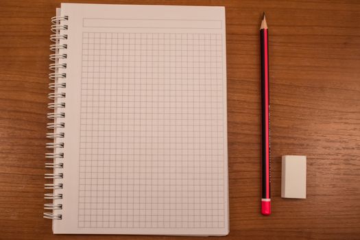 Pencil, eraser and notebook on the wooden table