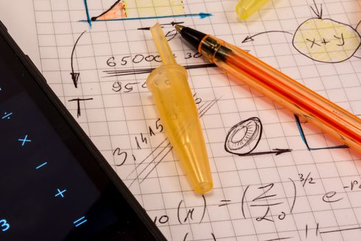 Notebook full of mathematics. Smart phone and pencils are visible