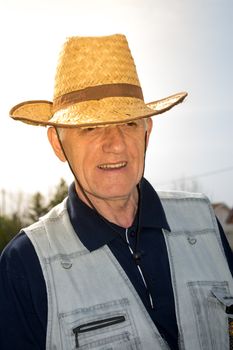 Elderly farmer with hat watering crops in early spring